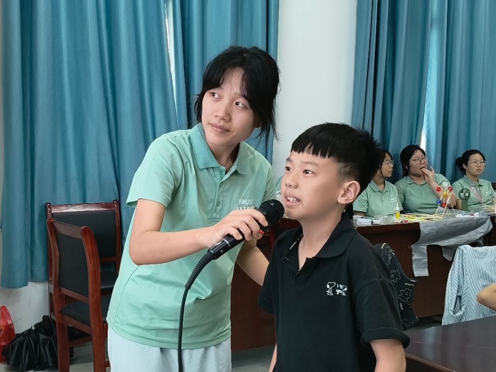志愿者手持话筒辅助学生发言,引导学生清晰表达自己的想法